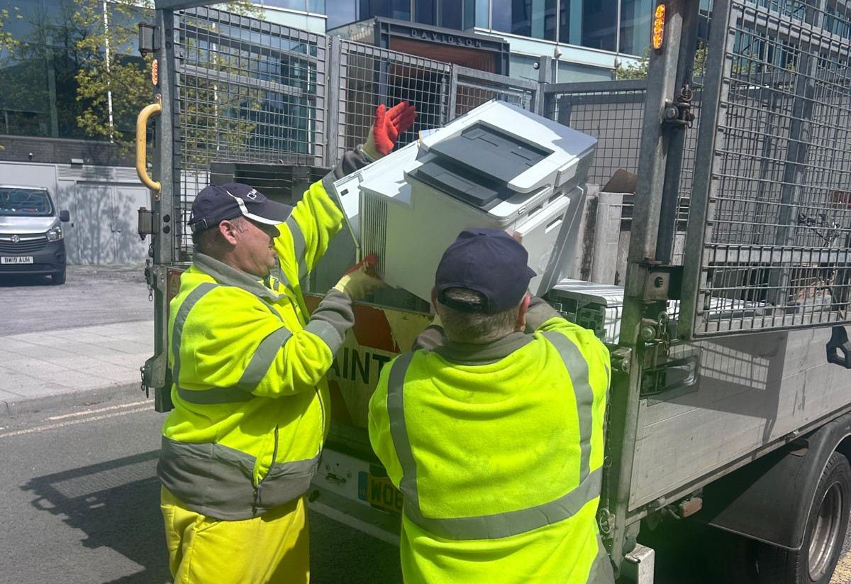 Two men in high vis moving small electricals into a truck